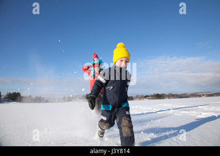 Father and two sons fooling around, running through snow covered landscape Stock Photo