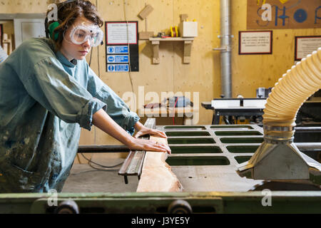 Young woman using machinery in a wood workshop Stock Photo