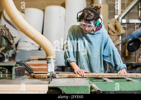 Young woman using machinery in a wood workshop Stock Photo