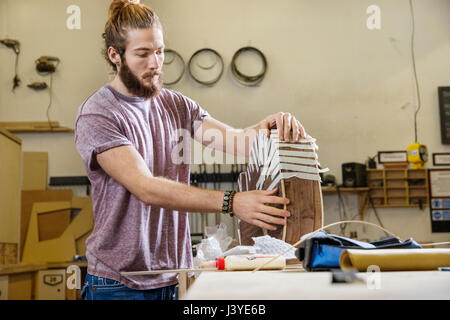 Young man constructing an acoustic guitar in a workshop Stock Photo