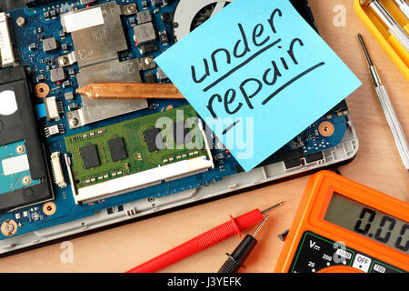 Broken laptop and stick with words under repair. Stock Photo