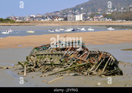 Shipwreck boat on the beach of Dives sur Mer in France with the commune of Hougalte in the background, in the Calvados department in France Stock Photo
