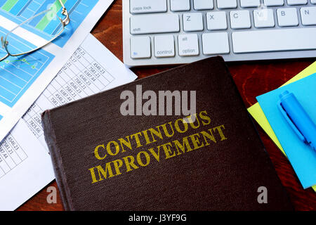 Book with title continuous improvement on a table. Stock Photo