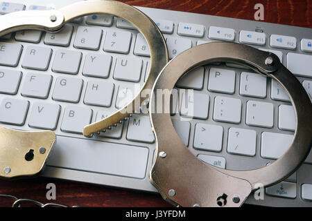 Hacking concept. Handcuffs on the keyboard. Stock Photo