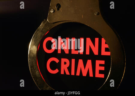 Words Online crime on a monitor and handcuffs. Stock Photo