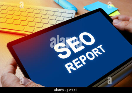Notepad in hands with message SEO report. Stock Photo