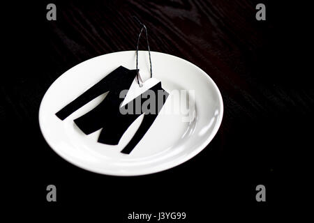 The little jacket is cut from velvet paper. On the plate, which stands on dark wooden background Stock Photo