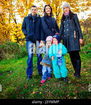 Young family, parents with small children in golden autumn Stock Photo