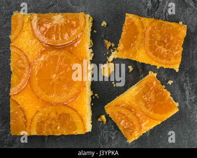 Glazed Candied Orange Sponge Cake on a Black Tile Background Stock Photo