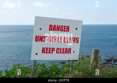 Sign warning of danger due to unstable cliffs on the South West Coast Path near Thurlestone in the South Hams, Devon Stock Photo