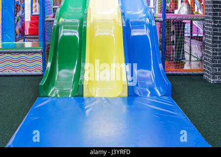 Three multi-colored slides with a soft mat at the bottom in the children entertainment center Stock Photo