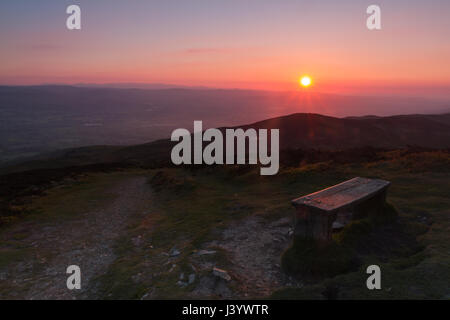 Sunset over a bench near the summit of Moel Famau on the Offa's Dyke path in Clwyd, North Wales. Stock Photo
