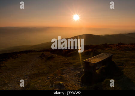 Sunset over a bench near the summit of Moel Famau on the Offa's Dyke path in Clwyd, North Wales. Stock Photo