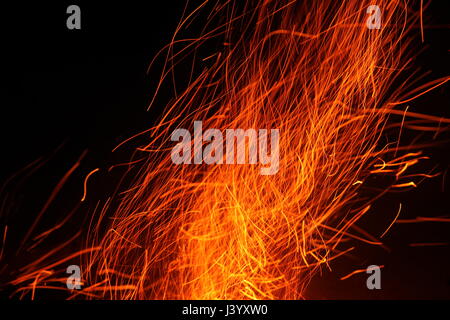 Red hot sparks fly up from the wood being burnt on a bonfire Stock Photo