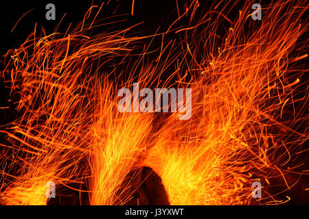Red hot sparks fly up from the wood being burnt on a bonfire Stock Photo