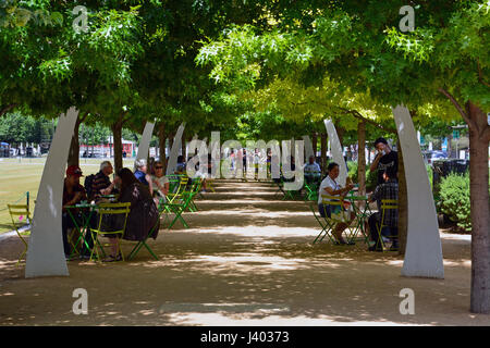 Public seating under oak trees and decorative arches line the promenade at Klyde Warren Park located above a recessed freeway in downtown Dallas Stock Photo