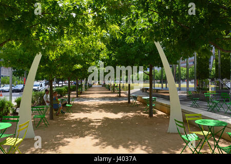 Public seating under oak trees and decorative arches line the promenade at Klyde Warren Park located above a recessed freeway in downtown Dallas Stock Photo