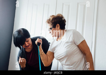 Woman helping senior woman to use resistance band Stock Photo