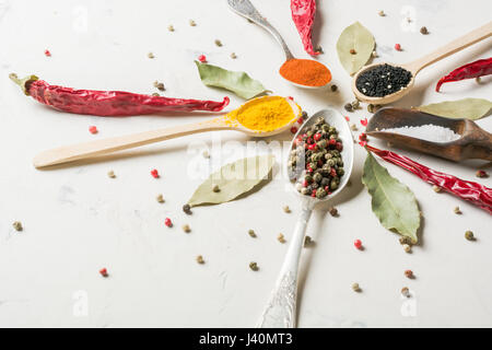 Spices in different spoons on a stone white background. Stock Photo
