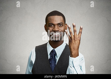 Closeup portrait, headshot, happy, smiling young man making four times sign gesture with hand fingers, isolated black grey background. Positive emotio Stock Photo