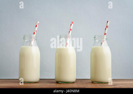 Retro milk bottles with paper drinking straw on blue background Stock Photo
