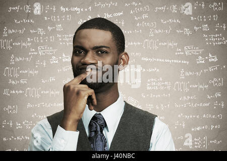 Closeup portrait young confused business man finger on lips, thinking deeply about something, looking puzzled, isolated black, grey background math fo Stock Photo