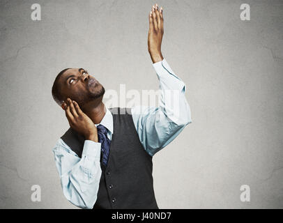 Closeup portrait young angry mad unhappy stressed man covering his ears looking up, to say stop making loud noise it's giving me headache isolated gre Stock Photo