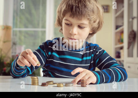 Little boy playing with coins making stacks. Learning finanncial responsibility and planning savings concept. Stock Photo