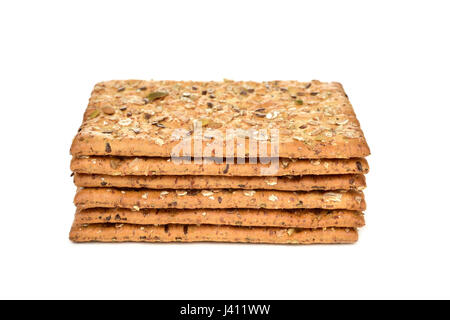 a pile of some appetizing brown crackers topped with different seeds on a white background Stock Photo