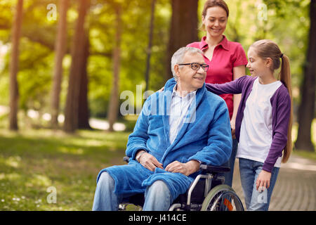 Happy wheelchair man with daughter and granddaughter in park Stock Photo