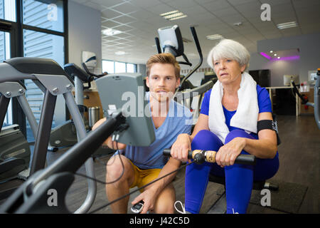 physiotherapist guiding senior woman on rowing machine Stock Photo