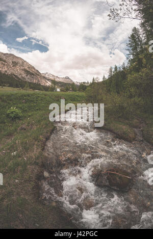 Flowing transparent waters on high altitude alpine stream in idyllic uncontaminated environment in the Italian French Alps. Ultra wide angle view. Stock Photo