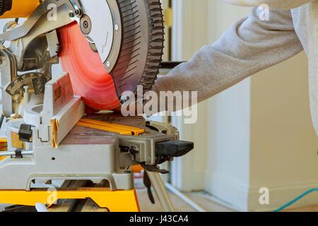 Carpenter cutting wooden plank with circular saw wearing safety equipment Stock Photo