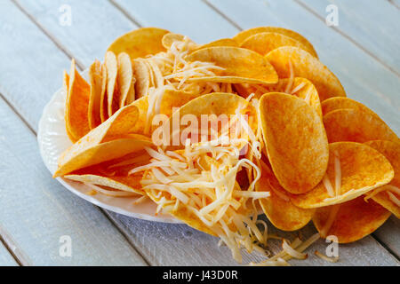 Crispy potato chips in a wicker bowl on old kitchen wood table chips with cheese Stock Photo
