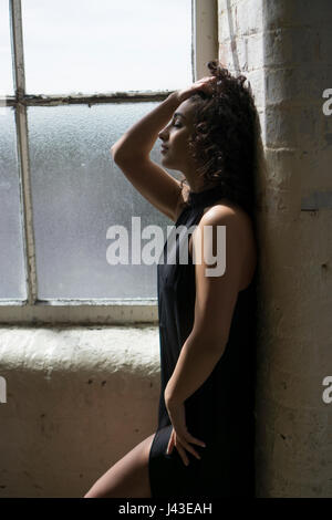 Sad young woman standing by the window Stock Photo