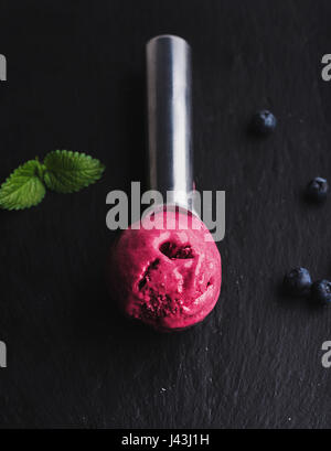 Blueberry ice-cream scoop over black slate stone background Stock Photo