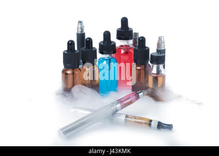 Thin e-cigarettes with glass bottles and smoke on white background Stock Photo