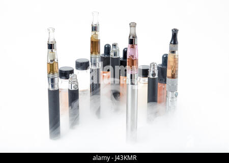 Thin e-cigarettes with glass bottles and smoke on white background Stock Photo