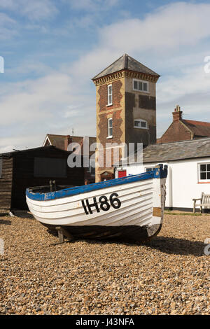 An old traditional fishing boat IH86 parked on the shingle beach in front of the old lifeboat station  at Aldeburgh Suffolk UK Stock Photo