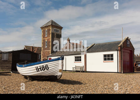 An old traditional fishing boat IH86 parked on the shingle beach in front of the old lifeboat station  at Aldeburgh Suffolk UK Stock Photo