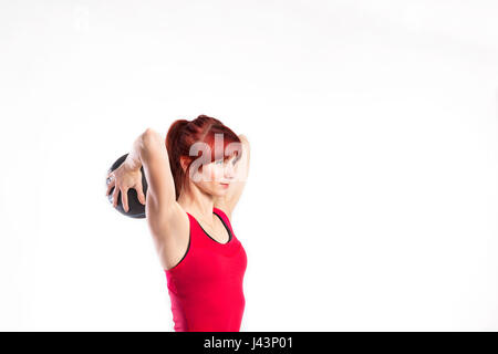 Fitness woman in red tank top holding medicine ball. Studio shot Stock Photo