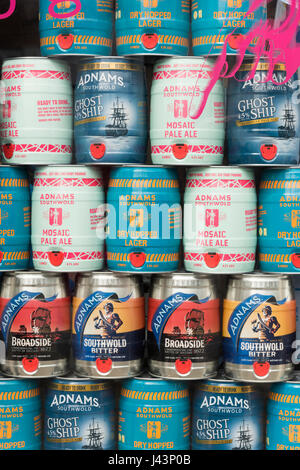 Metal barrels of beer brewed by the Adnams Brewery Suffolk piled up in a shop windoe Stock Photo