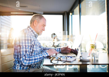 Senior businessman working on laptop in cafe Stock Photo