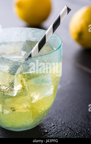 Cold Lemonade With Ice Cubes and Lemon on Dark Background Stock Photo