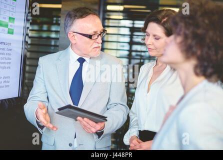 Coworkers discussing project by using digital tablet Stock Photo
