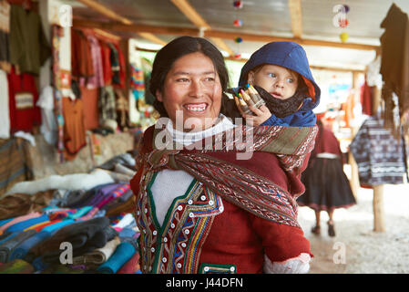 Cusco, Peru - April 21, 2017: Peruvian woman have fun with kid. Woman from Peru play with tourist kid Stock Photo