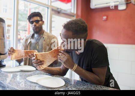 Two young men eating pizza. Stock Photo