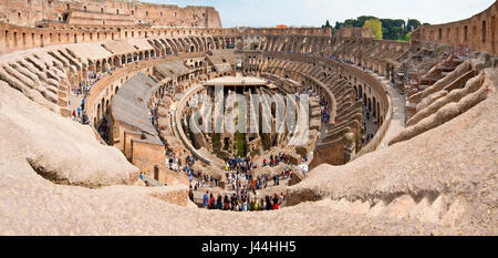 A 2 picture stitch panoramic interior view of the amphitheatre inside the Colosseum with tourists visitors on a sunny day taken from the top level 3. Stock Photo