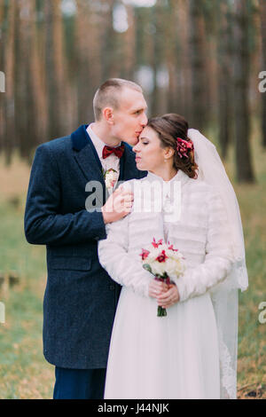 Happy stylish newlywed pair posing in conifer forest. Half-length portrait Stock Photo