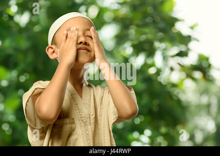 Little asian muslim child in traditional dress praying with abstract background Stock Photo